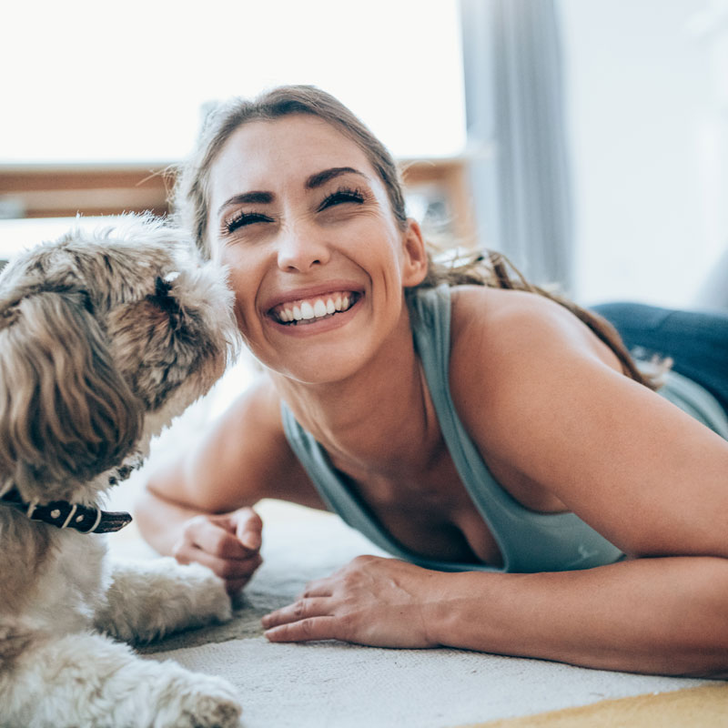 A woman playing with her dog after her Dental Implants Procedure at OKC Dentistry in Oklahoma City