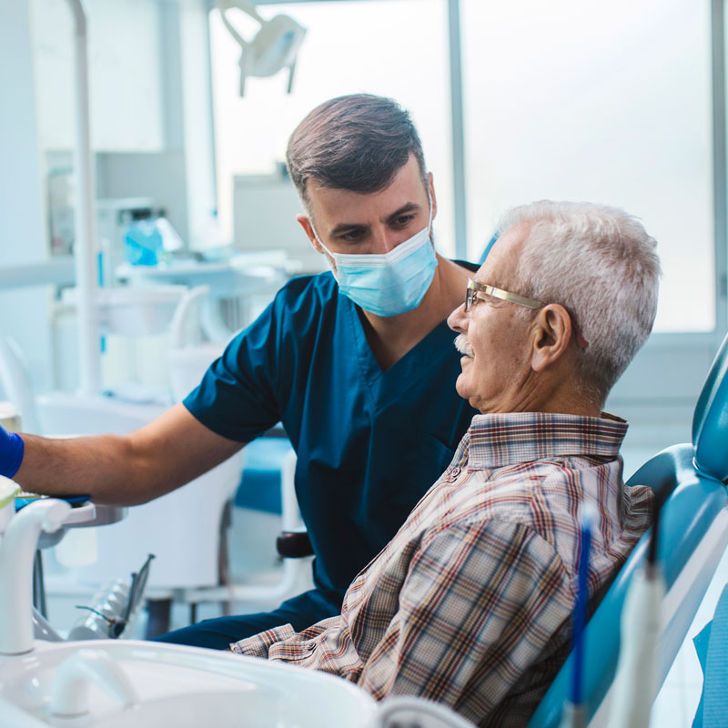 male dentist working with senior patient