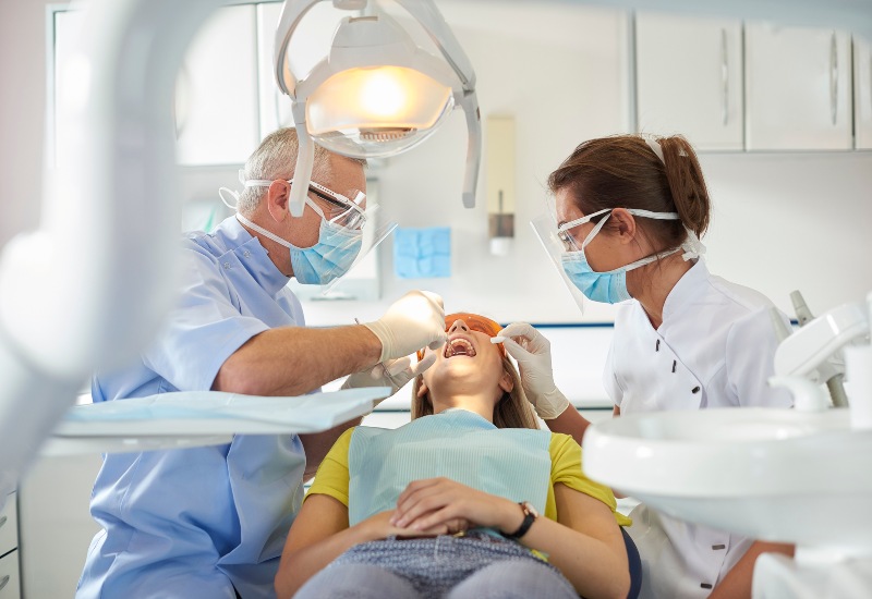 Family-friendly atmosphere at OKC Dentistry, with the dental team examining patient's oral health.