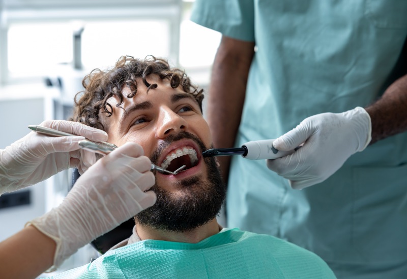 Professional dentist doing oral examination for surgery on bearded patient in Oklahoma City.